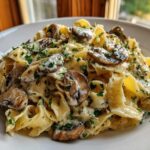 Close-up of creamy mushroom pasta featuring wide noodles, sliced mushrooms, and chopped parsley.