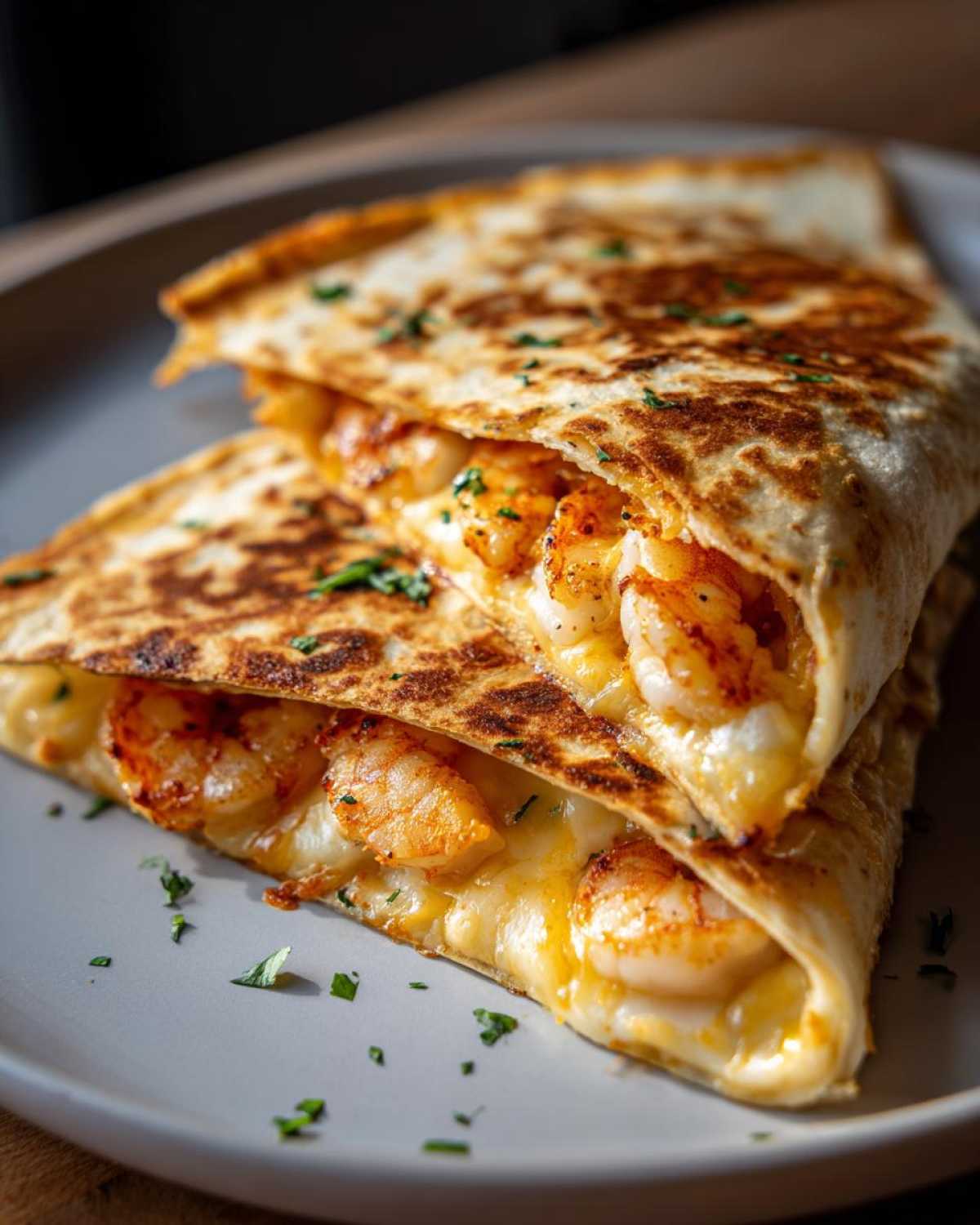 Close-up of two halves of a perfectly grilled shrimp quesadilla, oozing melted cheese and seasoned shrimp.