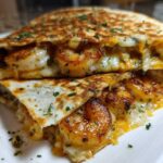Close-up of a perfectly grilled shrimp quesadilla, cut in half, showing seasoned shrimp and gooey melted cheese.