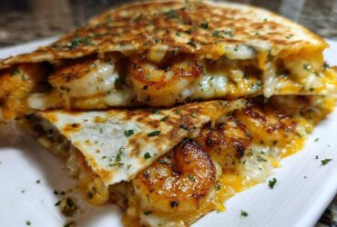 Close-up of a perfectly grilled shrimp quesadilla, cut in half, showing seasoned shrimp and gooey melted cheese.