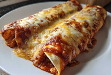 Close-up of two baked cheese enchiladas smothered in red sauce and melted white cheese.