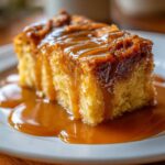 A close-up of a moist slice of bread pudding generously covered in rich bourbon sauce.
