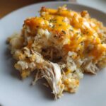 Close-up of a serving of chicken cauliflower rice casserole topped with melted cheddar cheese and parsley.