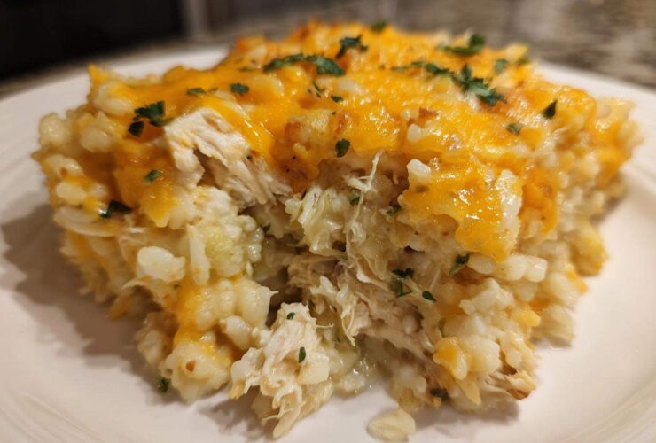 Close-up of a serving of chicken cauliflower rice casserole topped with melted cheddar cheese and parsley.