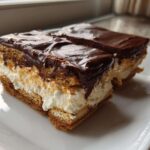 Two rectangular slices of amazing 3 layer chocolate eclair cake with creamy filling and rich chocolate topping.