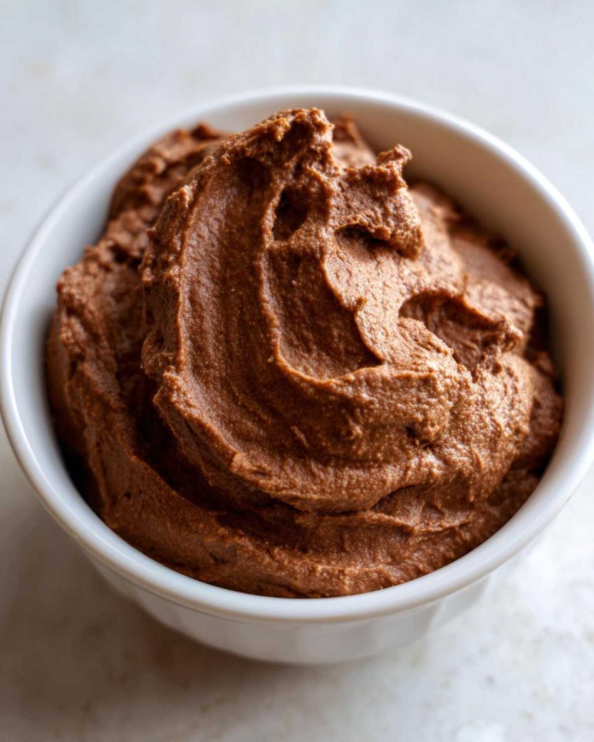 Close-up of rich, creamy chocolate dip swirled high in a small white bowl.