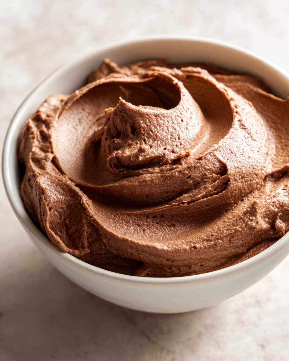 Close-up of a white bowl filled with fluffy, swirled, creamy chocolate dip.
