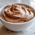 A close-up of creamy, swirled chocolate dip presented in a small white bowl.