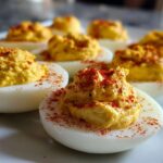 Close-up of creamy deviled egg filling topped with paprika, illustrating perfect egg preparation.