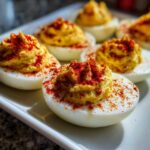Close-up of creamy deviled egg halves topped with paprika, showcasing the perfect egg filling.