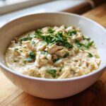 A close-up of creamy white chicken chili topped with fresh parsley in a white bowl.