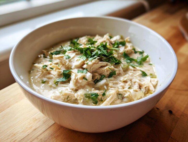 A close-up of creamy white chicken chili topped with fresh parsley in a white bowl.