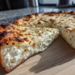 A thick slice of creamy white pizza showing a rich, white ricotta filling and a well-browned, slightly charred crust.