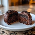 Close-up of one chocolate Oreo ball cut in half, showing the rich, dark interior filling and chocolate coating.