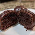 Close-up of one of the Oreo balls cut in half, showing the dense chocolate center and thick chocolate coating.
