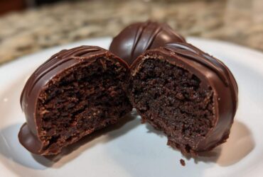 Close-up of one of the Oreo balls cut in half, showing the dense chocolate center and thick chocolate coating.