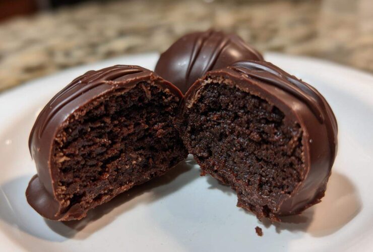 Close-up of one of the Oreo balls cut in half, showing the dense chocolate center and thick chocolate coating.