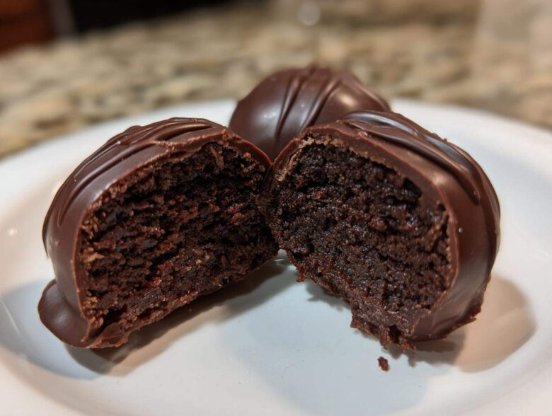 Close-up of one of the Oreo balls cut in half, showing the dense chocolate center and thick chocolate coating.