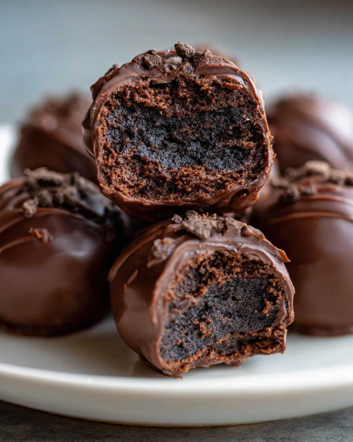 Close-up of chocolate-coated Oreo balls, one cut in half showing the dense, dark chocolate filling.