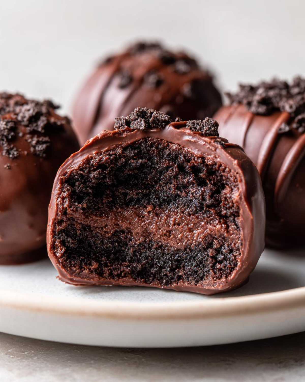 Close-up of a chocolate-dipped Oreo balls cut in half showing the rich dark cake interior and creamy filling.