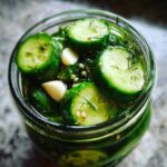 Top-down view of crisp cucumber slices, garlic cloves, and dill inside a jar of homemade refrigerator pickles.