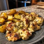 A plate of baked garlic parmesan chicken and potatoes, topped with melted cheese and herbs.