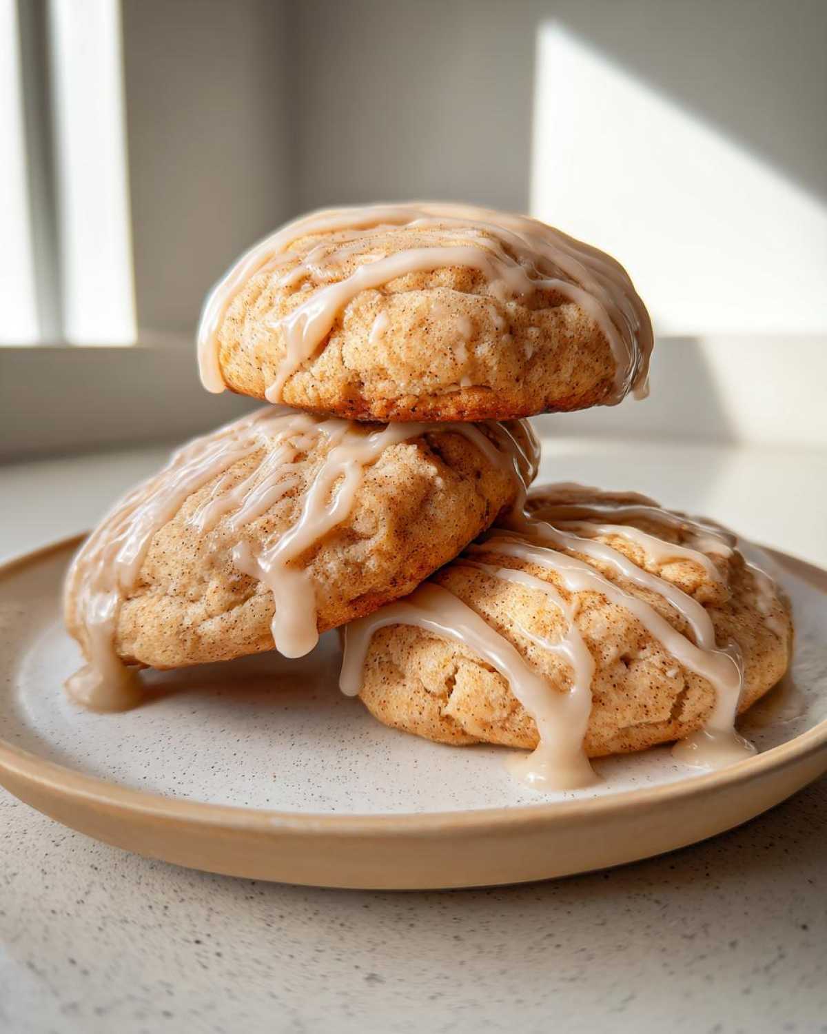 Three soft, thick apple pie cookies stacked and drizzled generously with a light brown glaze.