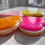 Close-up of heart-shaped sugar cookies decorated with bright orange, pink, and yellow sugar cookie icing recipe.