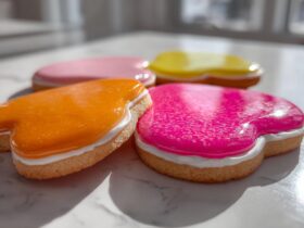 Close-up of heart-shaped sugar cookies decorated with bright orange, pink, and yellow sugar cookie icing recipe.