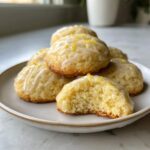 Stack of soft italian ricotta cookies drizzled with lemon glaze and zest.