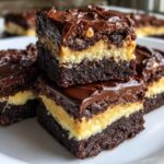 Close-up of stacked, decadent buckeye brownies showing three distinct layers: dark chocolate base, peanut butter filling, and chocolate ganache topping.
