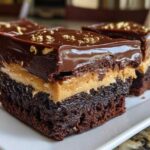 Three rich, layered buckeye brownies featuring a dark chocolate base, peanut butter filling, and glossy chocolate topping with gold sprinkles.