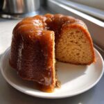 A slice cut from a bundt-style rum cake recipe, generously covered in a thick, glossy caramel glaze.