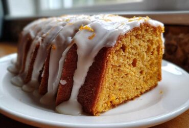 A thick slice of moist sweet potato pound cake drizzled with white glaze and orange zest.