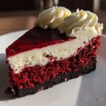 Close-up of a layered slice of red velvet cheesecake with cream cheese frosting.