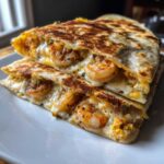 Close-up of a perfectly grilled shrimp quesadilla cut in half, showing melted cheese and seasoned shrimp filling.