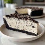 A close-up of a creamy slice of oreo pie with a dark cookie crust, topped with cookie crumbs.