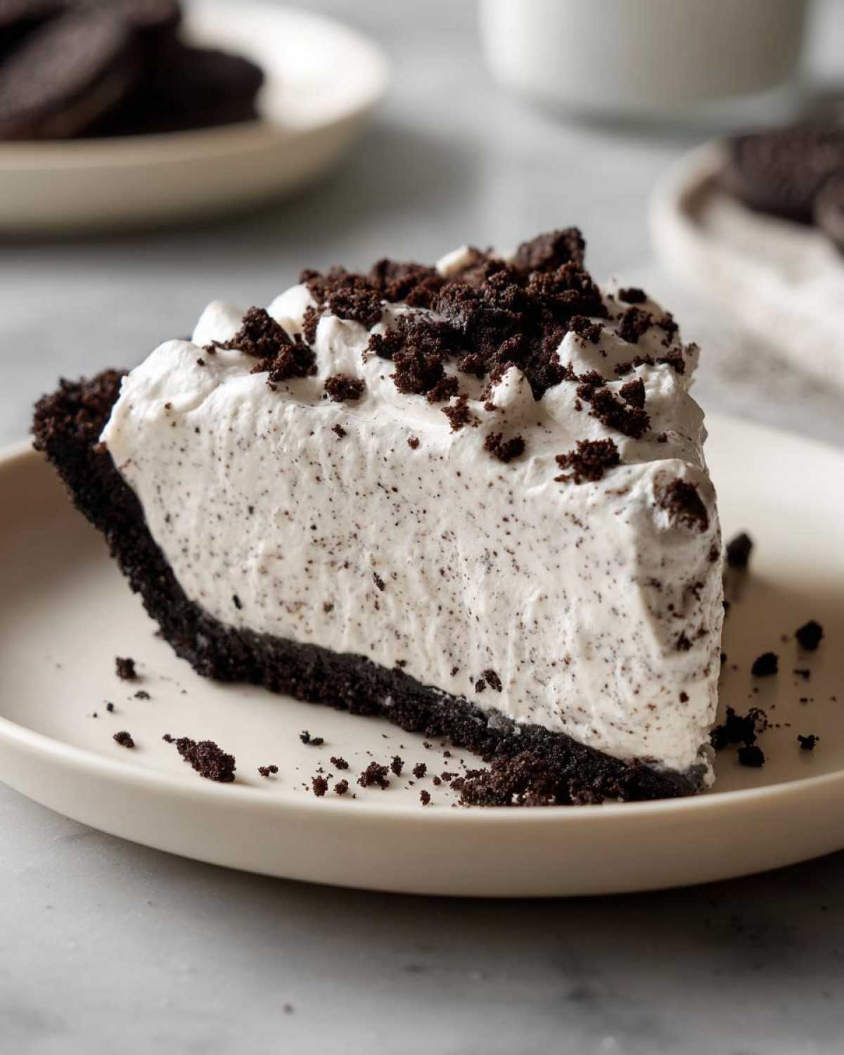 A generous slice of creamy, no-bake Oreo pie with a dark chocolate crust and crumbled topping.