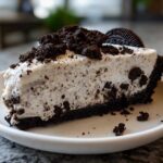 Close-up of a creamy slice of oreo pie with a dark chocolate crust and crumbled topping.