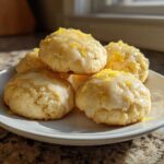 A stack of soft italian ricotta cookies topped with a white lemon glaze and bright yellow zest.