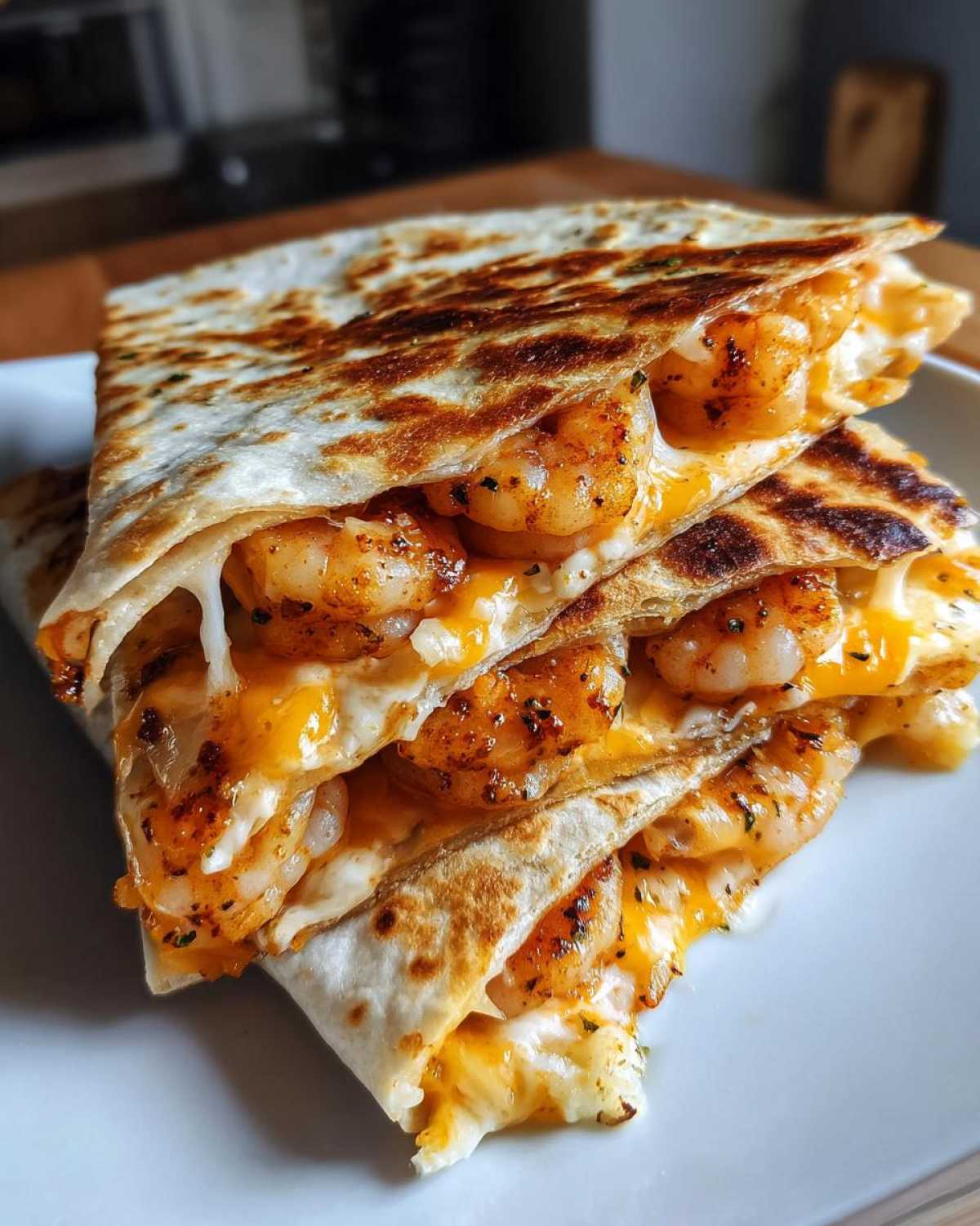 Close-up of stacked, golden-brown shrimp quesadilla wedges oozing with melted cheese and seasoned shrimp.