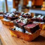 Close-up of a slice of steak crostini featuring medium-rare steak, creamy cheese, and balsamic glaze on toasted bread.
