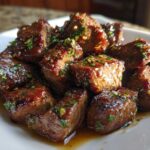 Close-up of tender, glazed cubes of hibachi steak topped with green herbs.