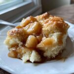 A close-up of a warm serving of apple bubble up casserole, showing soft dough pieces covered in cinnamon apple filling.