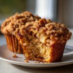 Close-up of a delicious apple oatmeal muffin, broken open to show the moist interior and chunks of apple.