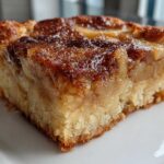 Close-up of a moist, square slice of apple pie dump cake showing the soft cake base and caramelized apple topping.