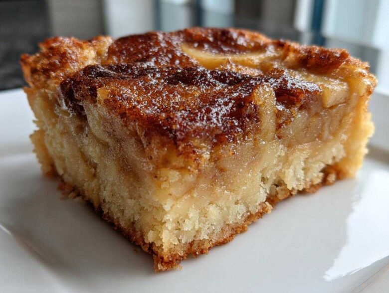 Close-up of a moist, square slice of apple pie dump cake showing the soft cake base and caramelized apple topping.
