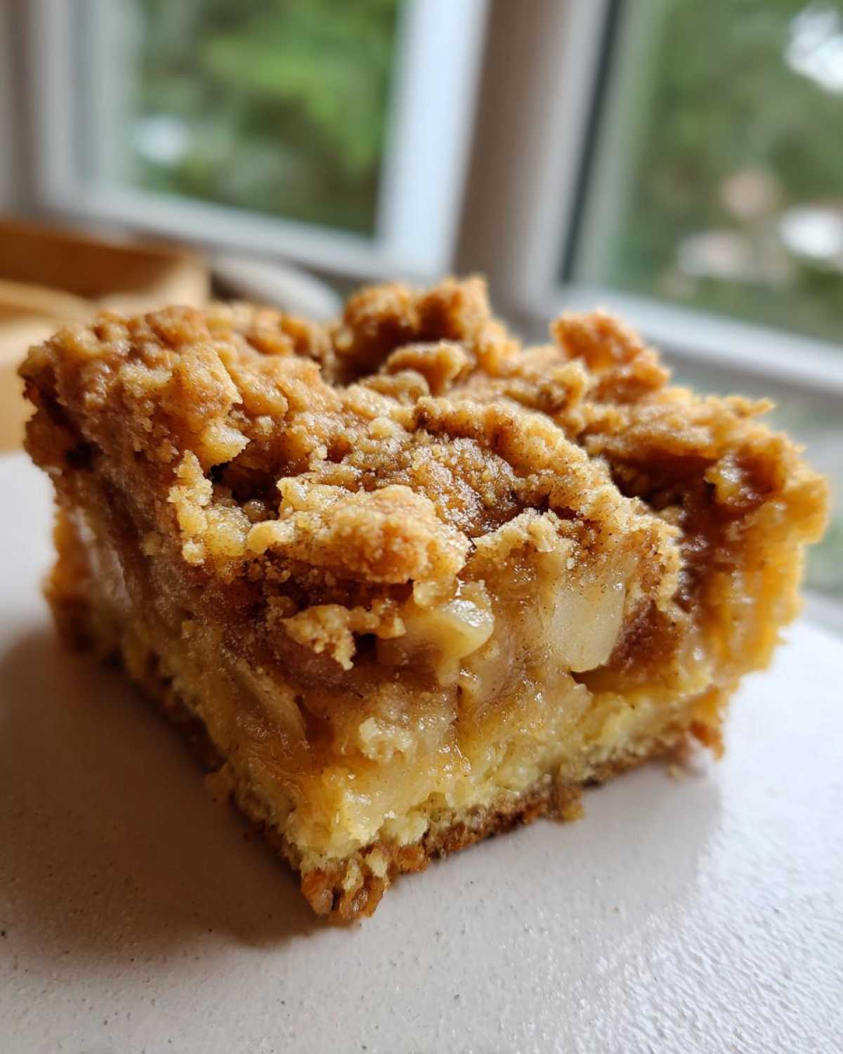 A close-up of a moist square of apple pie dump cake with a crumbly topping.