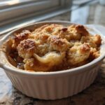 Close-up of a single serving of the best apple cobbler in a white ramekin, featuring golden, crumbly topping.