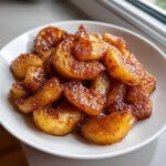 Close-up of perfectly caramelized pan fried cinnamon apples piled high in a white bowl.
